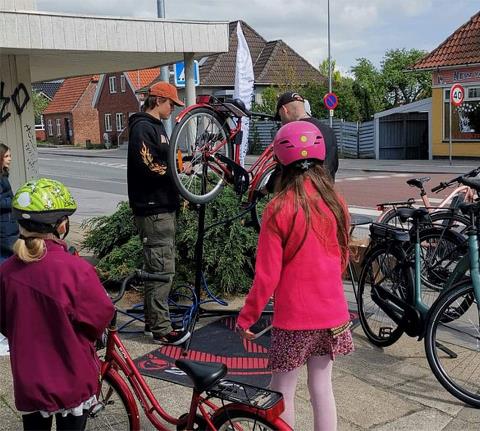 Cykelsmed der servicerer to unge pigers cykler i forbindelse med cyklistkampagne. 